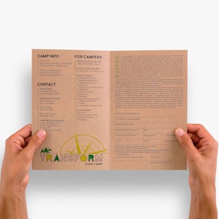 Two hands holding open a school brochure printed with camp details, contact information and a waiver.