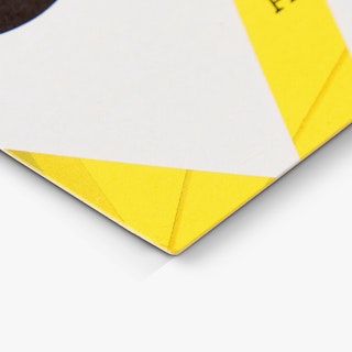 The bottom corner of a custom business card printed with an abstract black, yellow and white design.