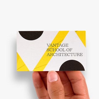 A hand holding a business card printed with Vantage School of Architecture in black, white and yellow.