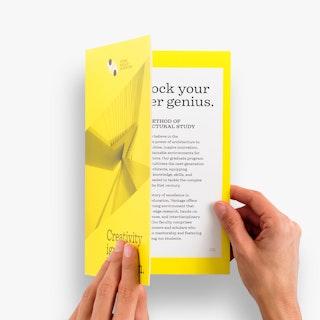 Two hands opening a saddle stitch booklet printed with information about an architecture school.