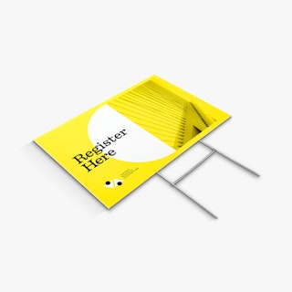 A yard sign and H-stake laying flat with a yellow and white design and Register Here in black.