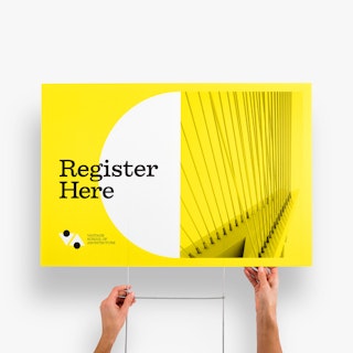 Two hands holding a custom yard sign and H-stake with Register Here and a yellow, white and black design.