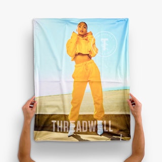 Two hands holding a silicone edge graphic printed with a woman in yellow sweats and Threadwell.