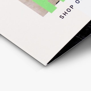 The bottom corner of a folded self-mailer printed with a white, gray and green design.
