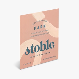 A square roll label printed with a cream and tan design and Double Origin Dark.