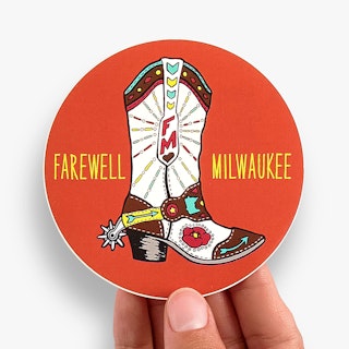 A hand holding a custom sticker printed with a round shape, orange background and Farewell Milwaukee.