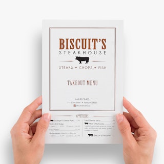 Two hands holding a restaurant take-out menu printed with Biscuit's Steakhouse and appetizers on the front.
