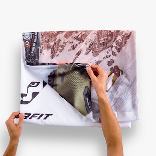 Two hands unfolding a tension fabric display replacement graphic printed with a ski scene and ski boot.