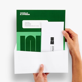 Two hands holding a green and white letter mailer and reply envelope coming out of a white envelope.