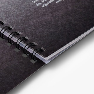 A custom booklet bound with black wire coils through square drill holes.